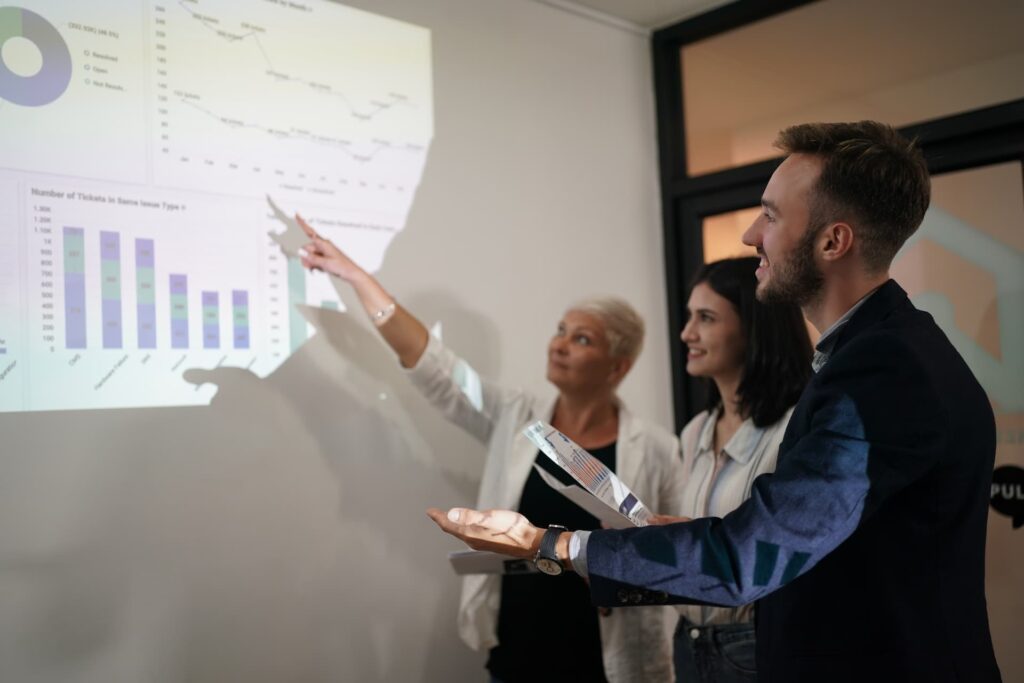 A team analyzing performance data, pointing at charts and metrics displayed on a screen during a strategy meeting