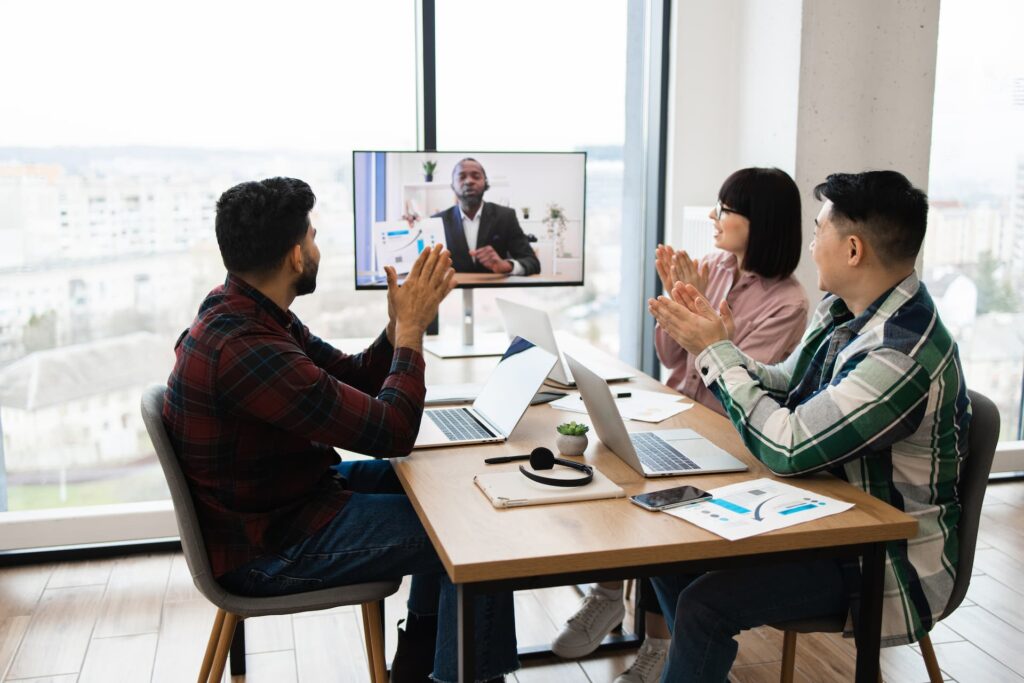 A team video conferencing, discussing project details and celebrating success with applause