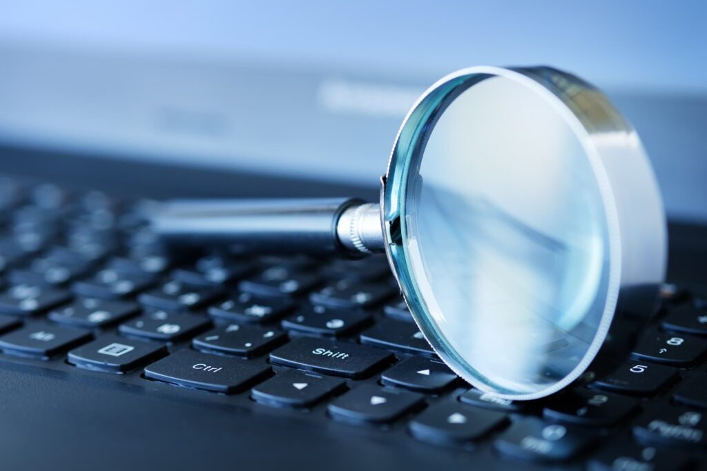 Magnifying glass on top of the keyboard — Top BPO Solutions | Outsourcing Services In The Philippines