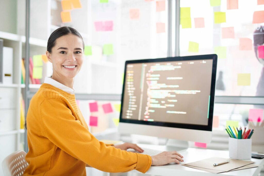 Woman smiling in front of her monitor — Top BPO Solutions | Outsourcing Services In The Philippines