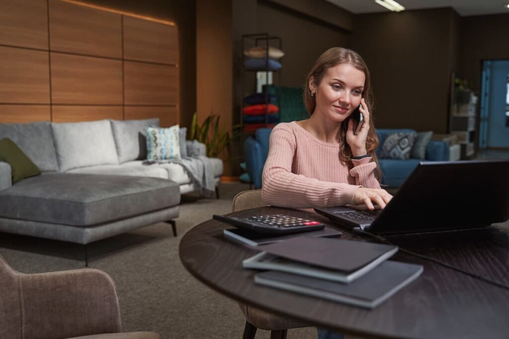 Pleased focused young sales person typing on laptop