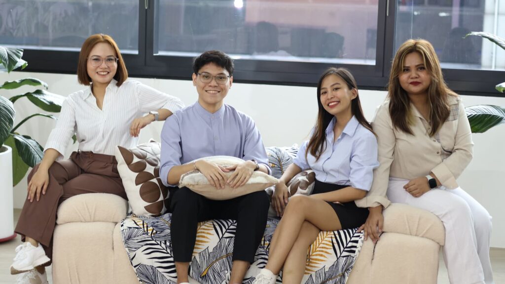 Happy team sitting on a couch — Business process outsourcing & offshore staffing | Sourcefit