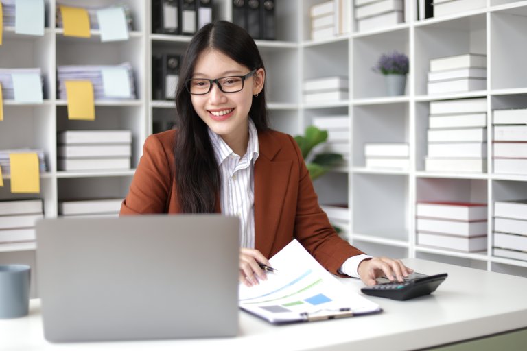 Happy Asian businesswoman working analyzing financial documents— Business process outsourcing & offshore staffing | Sourcefit