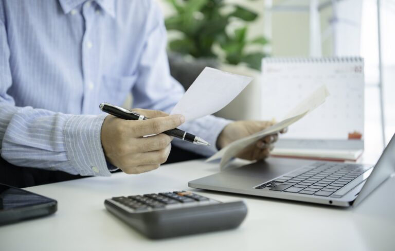 Man reviewing invoices with calculator: Offshore Staffing & BPO Across 6 Countries