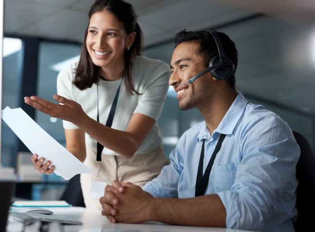Shot of a young man and woman reading a document while working in a call centre Shot of a young man and woman reading a document while working in a call centre
